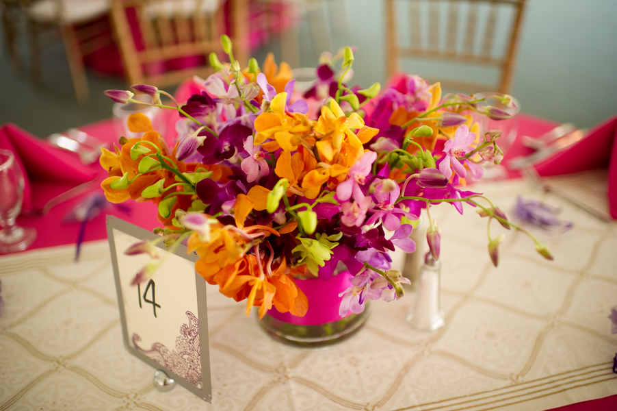 white and gold table runner over hot pink tablecloth with floral centerpiece for wedding and table number