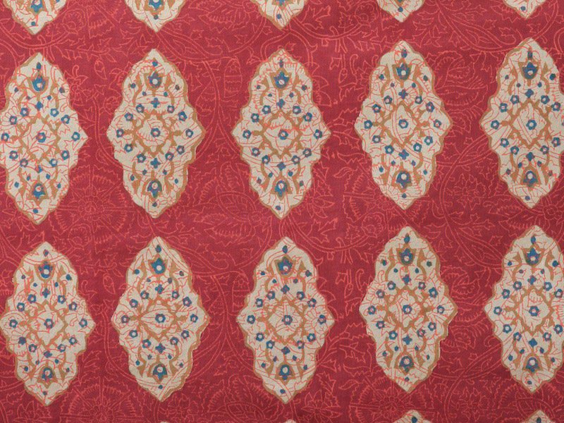 floral filigree of cinnamon, turmeric and imperial blue on a rich red orange ground