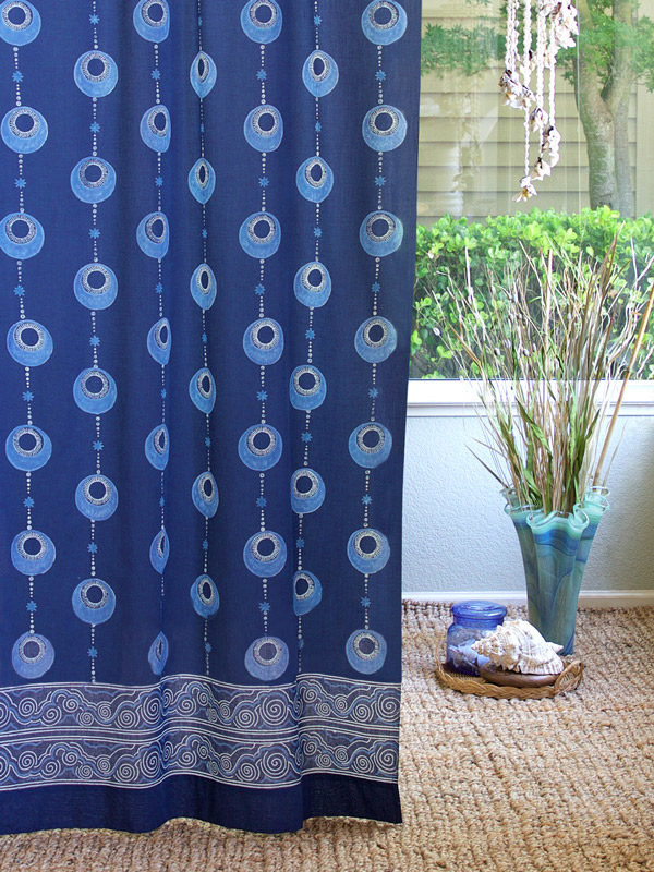 A vintage island style curtain with a blue bohemian pattern hangs at the window, making for elegant coastal decor.