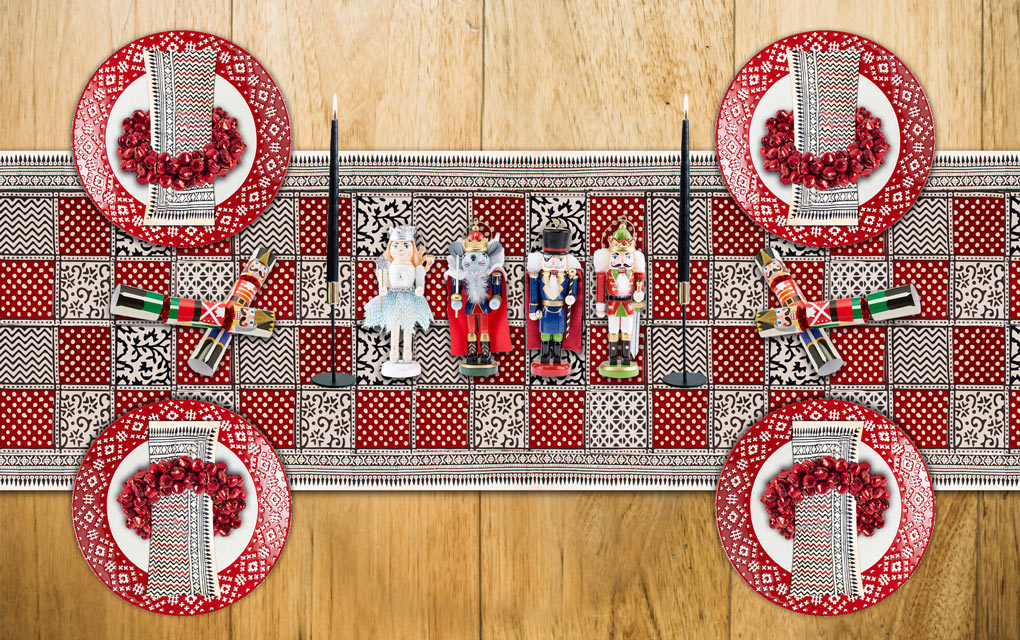 A black and red Christmas table runner with polka dots and a nutcracker centerpiece for a Christmas table setting