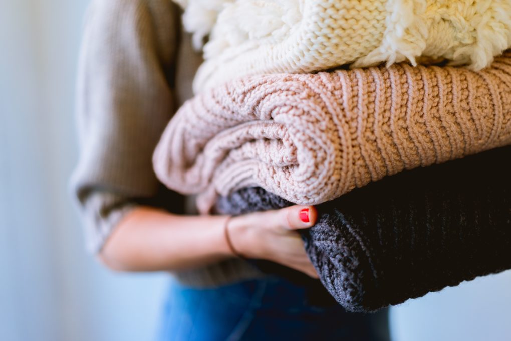 woman carrying stack of fresh blankets