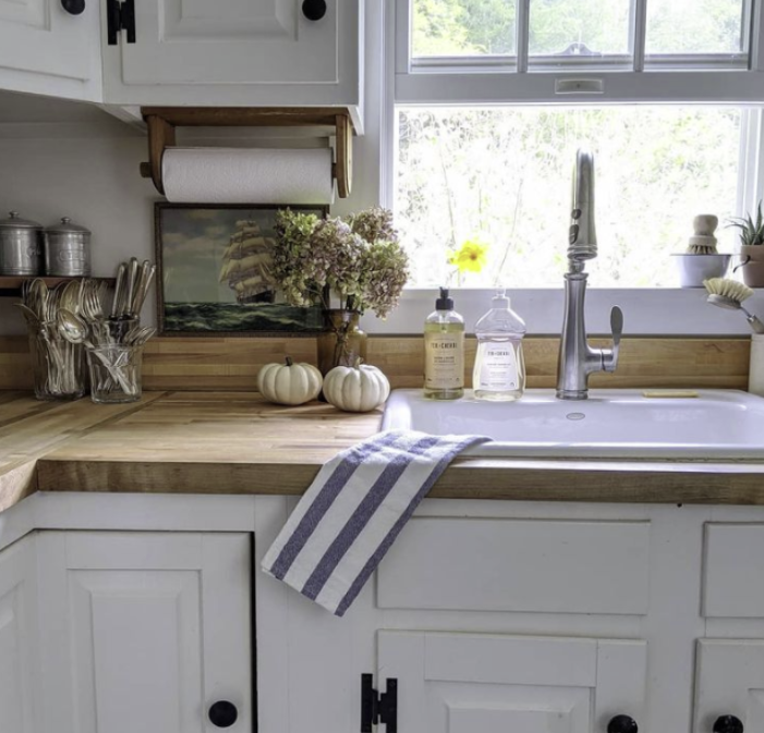 White kitchen, wood counters, white pumpkins, striped towel