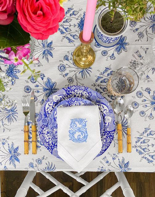 white and blue tablecloth with classic floral print, monogrammed napkins, pink candles and flowers
