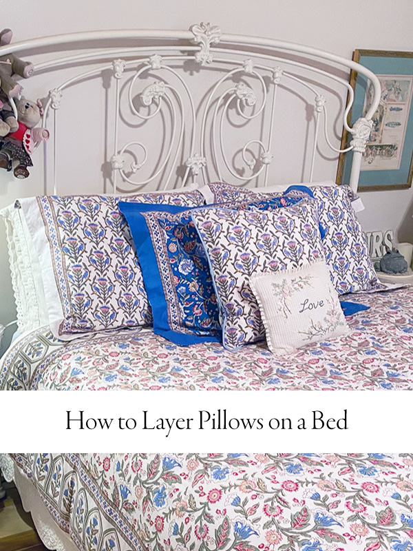Multicolor bedding with five pillows arranged on a white, wrought metal bed
