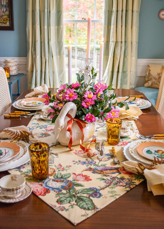 Dining table with table setting of floral table runner, flower centerpiece