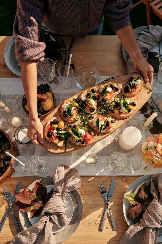 Photograph of a woman holding a brunch charcuterie board filled with open-face sandwiches.