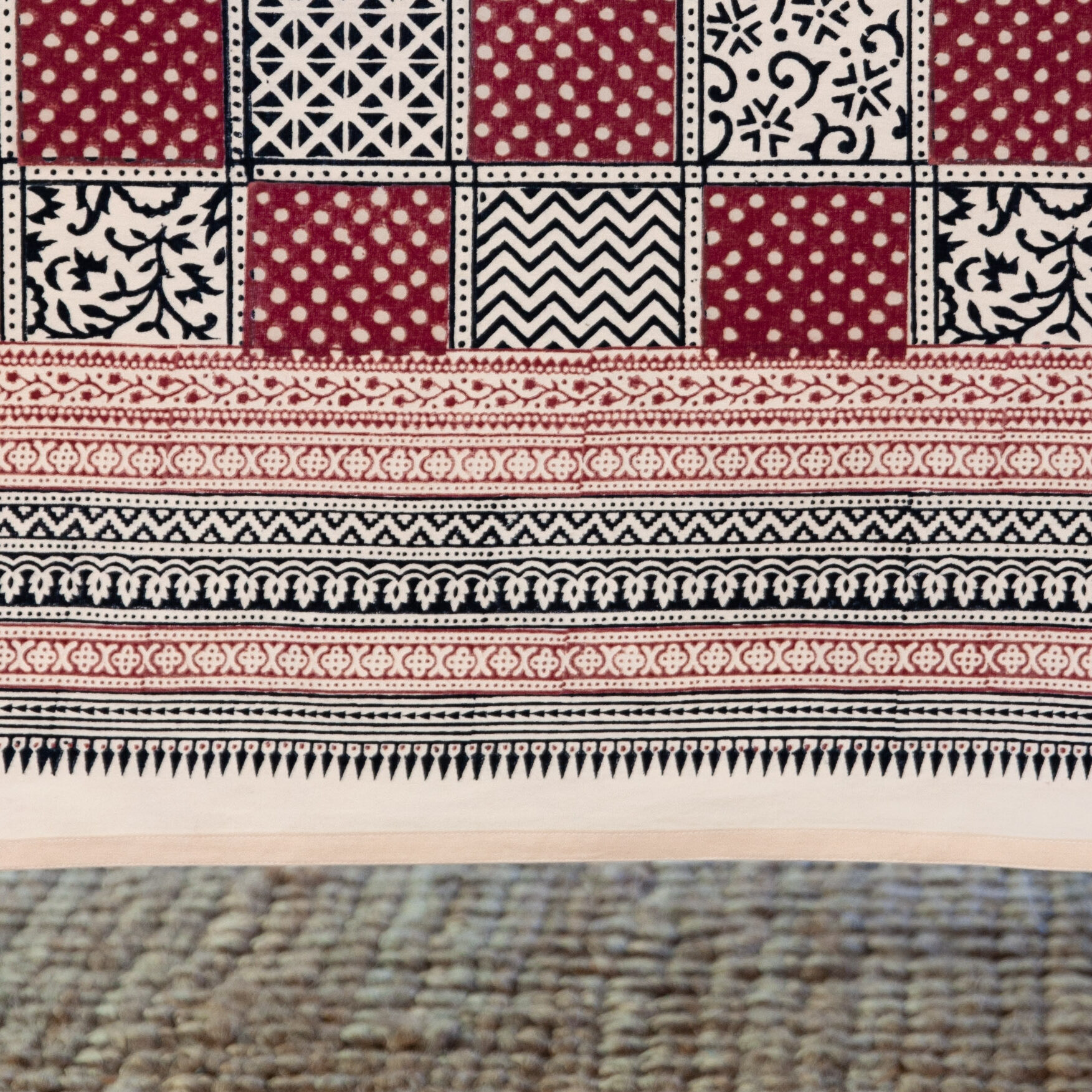 Image of a Christmas print swatch featuring a traditional border of red, black, and cream