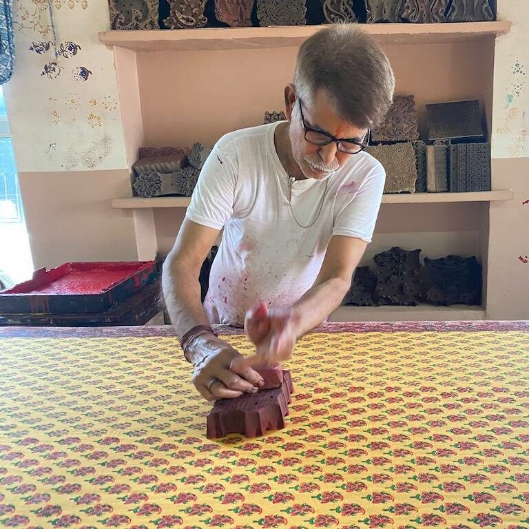 Artisan stamping down a paisley print on orange fabric