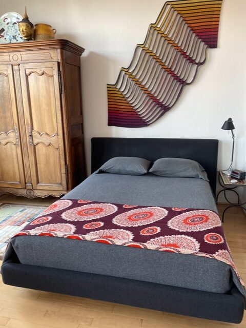Modern boho style bedroom using a quilt sari throw and unique wall art