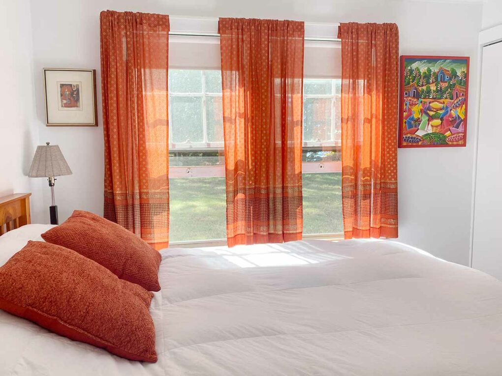 Modern bohemian style bedroom using jewel tone curtains and pillows and boho wall art