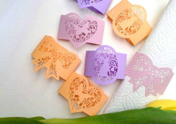 Example of paper napkin rings and holders featuring laser-cut designs on pastel papers