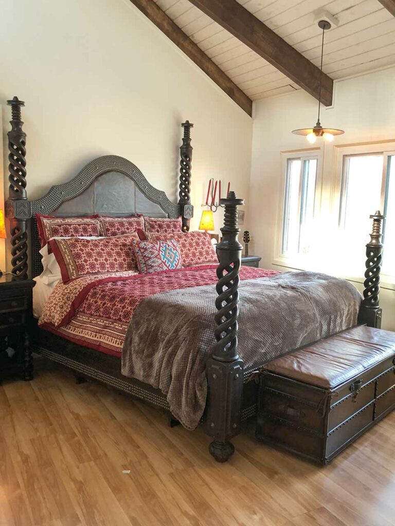 Photograph of neutral white and brown bedroom that uses a red pop of color in the bedding
