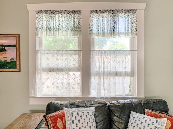 Photograph of a living room sofa and window showcasing what is transitional interior design through symmetric decor details