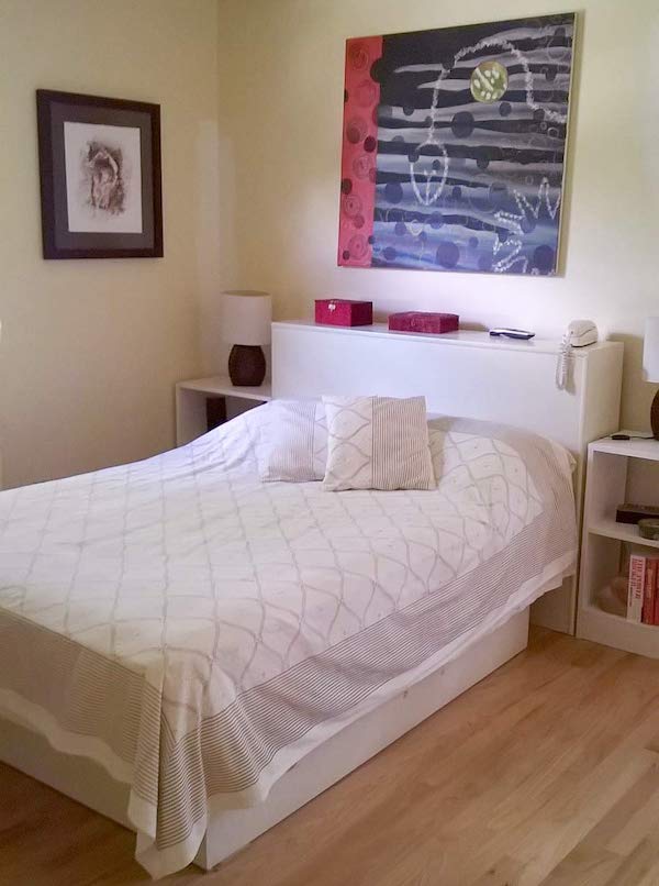 Photograph of a bedroom with a bed that has underneath storage, demonstrating small guest room ideas for maximizing hospitality